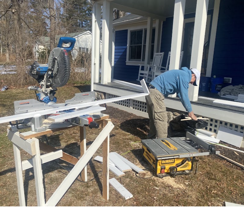 Carpentry work in progress beside a blue home's porch