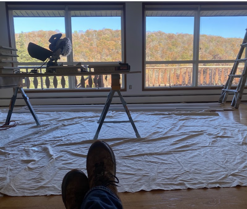 Interior project with a miter saw and protective floor coverings by large windows